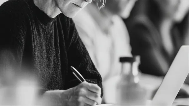 A person writing notes by hand at a table.