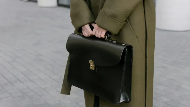 A person in a long coat holding a leather briefcase.